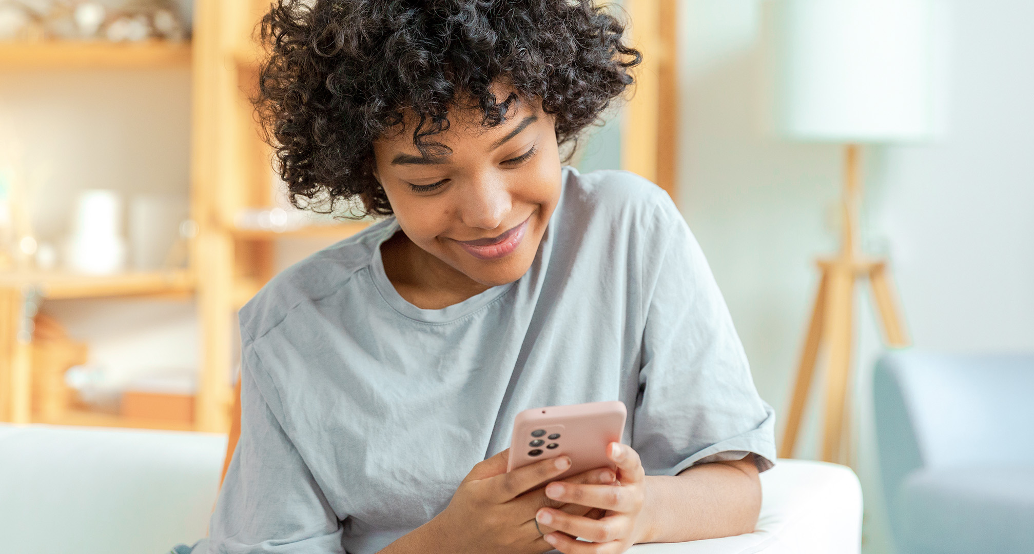 primeiro plano de uma pessoa a sorrir e a olhar para o telemóvel