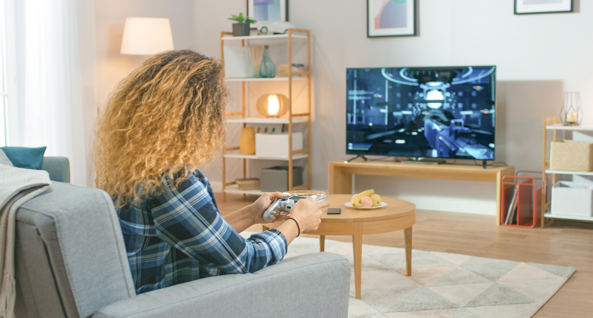 pessoa com cabelo comprido e encaracolado na sala a jogar videojogos numa televisão