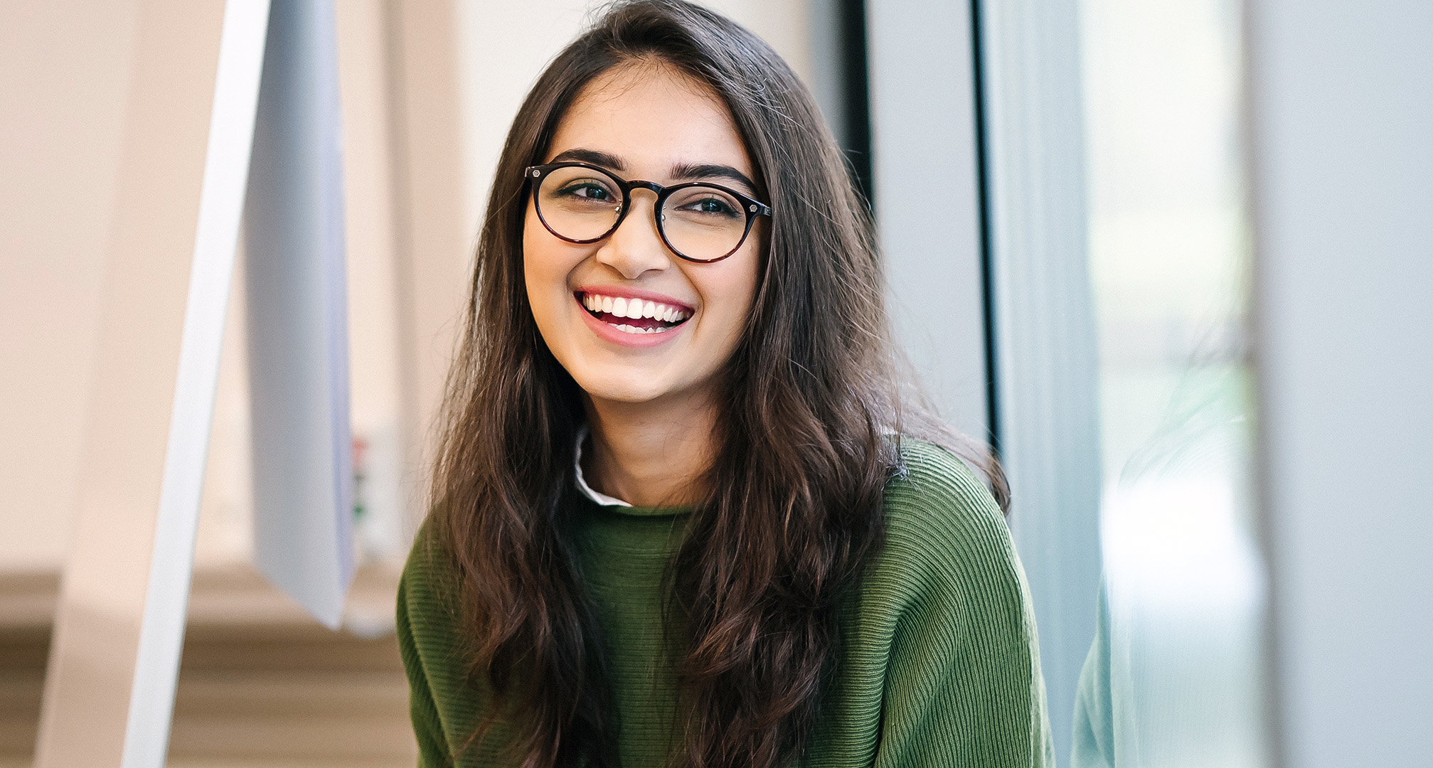 foto de uma pessoa sorridente com cabelo comprido e óculos de armação preta