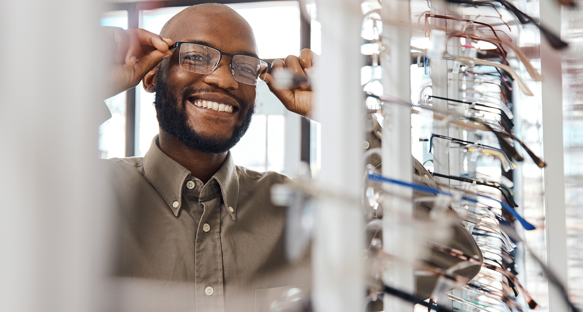 foto de uma pessoa sorridente a experimentar óculos na ótica